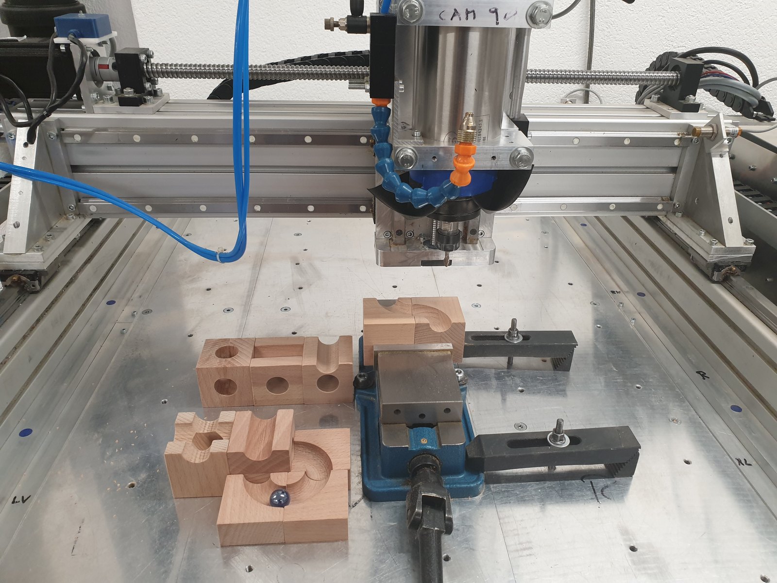 Fertig gefräste Kugelbahn-Elemente aus Holz auf dem Tisch der CNC-Fräse mit Schraubstock