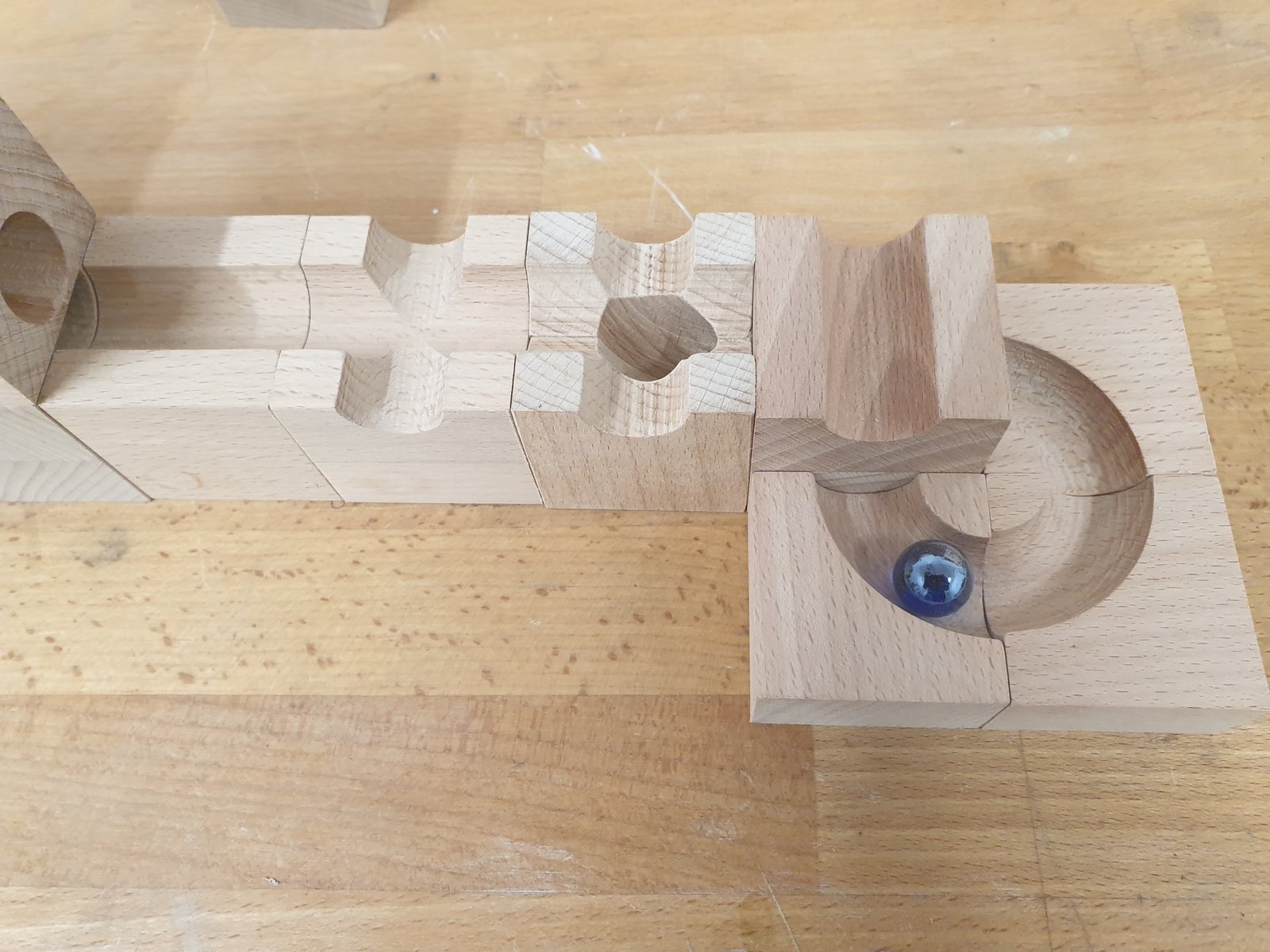 Detail der Kugelbahn-Elemente: Rinnen, Verzweigung und Trichter mit blauer Glaskugel